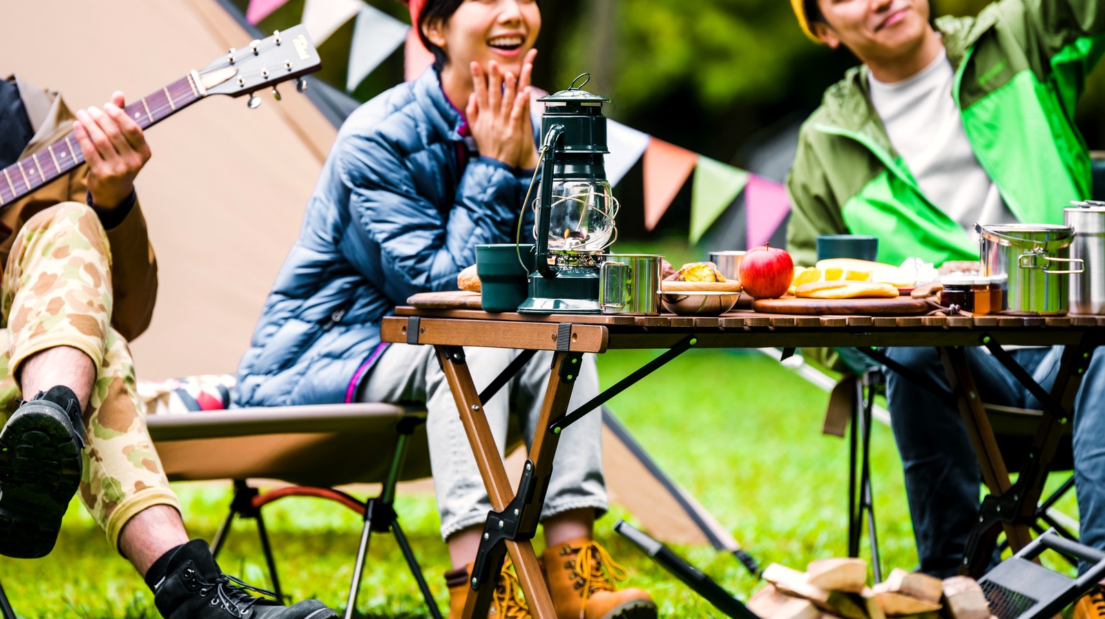 夏のキャンプでランタンを囲み食事を楽しむ人たち