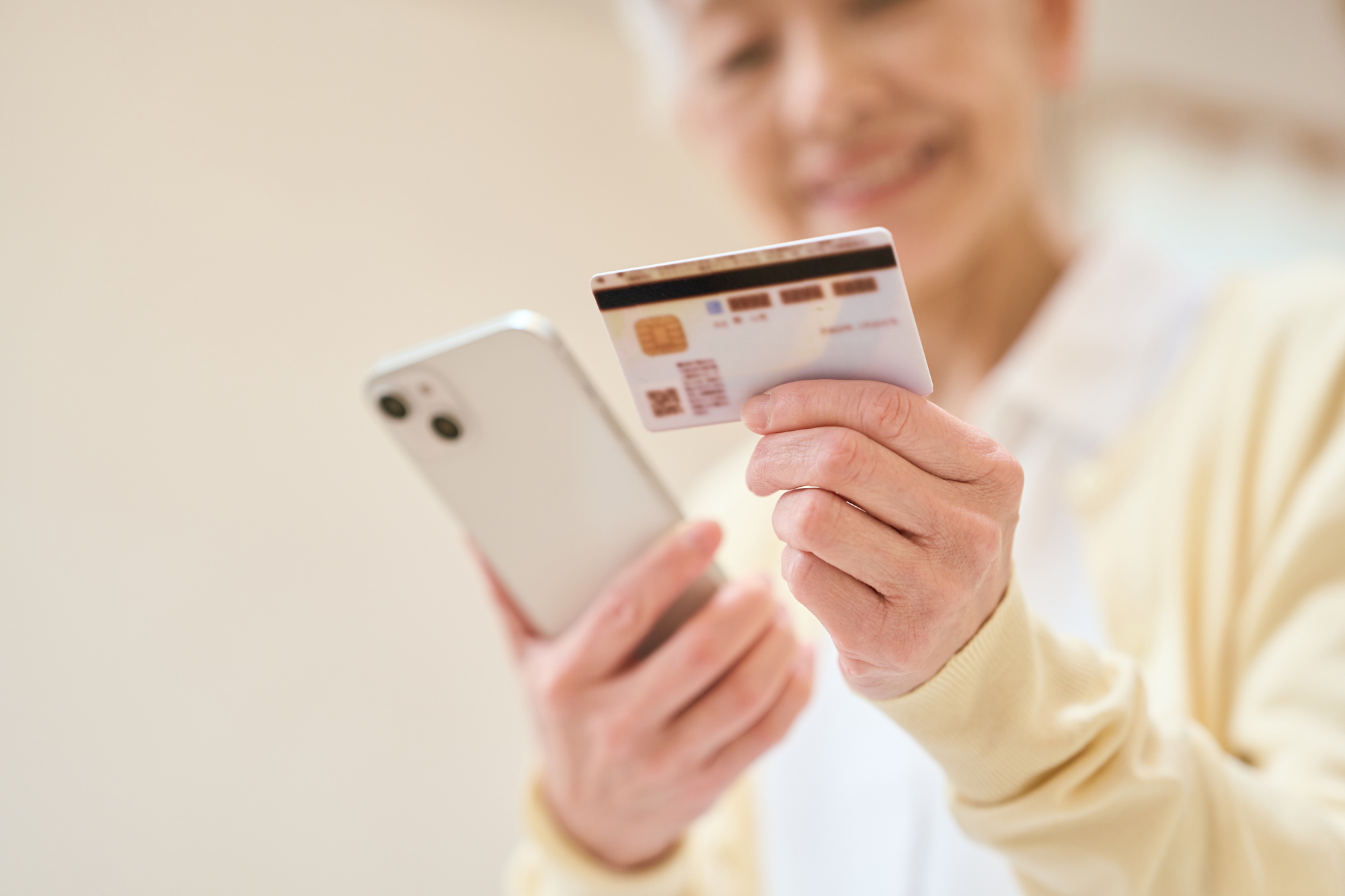 スマートフォンとクレジットカードを持って支払い方法を確認する人