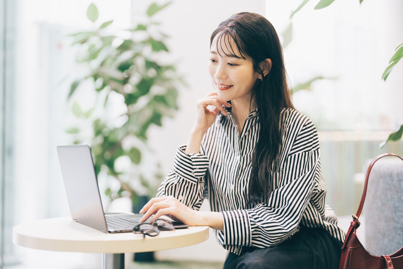 カフェでノートパソコンを使って作業する女性