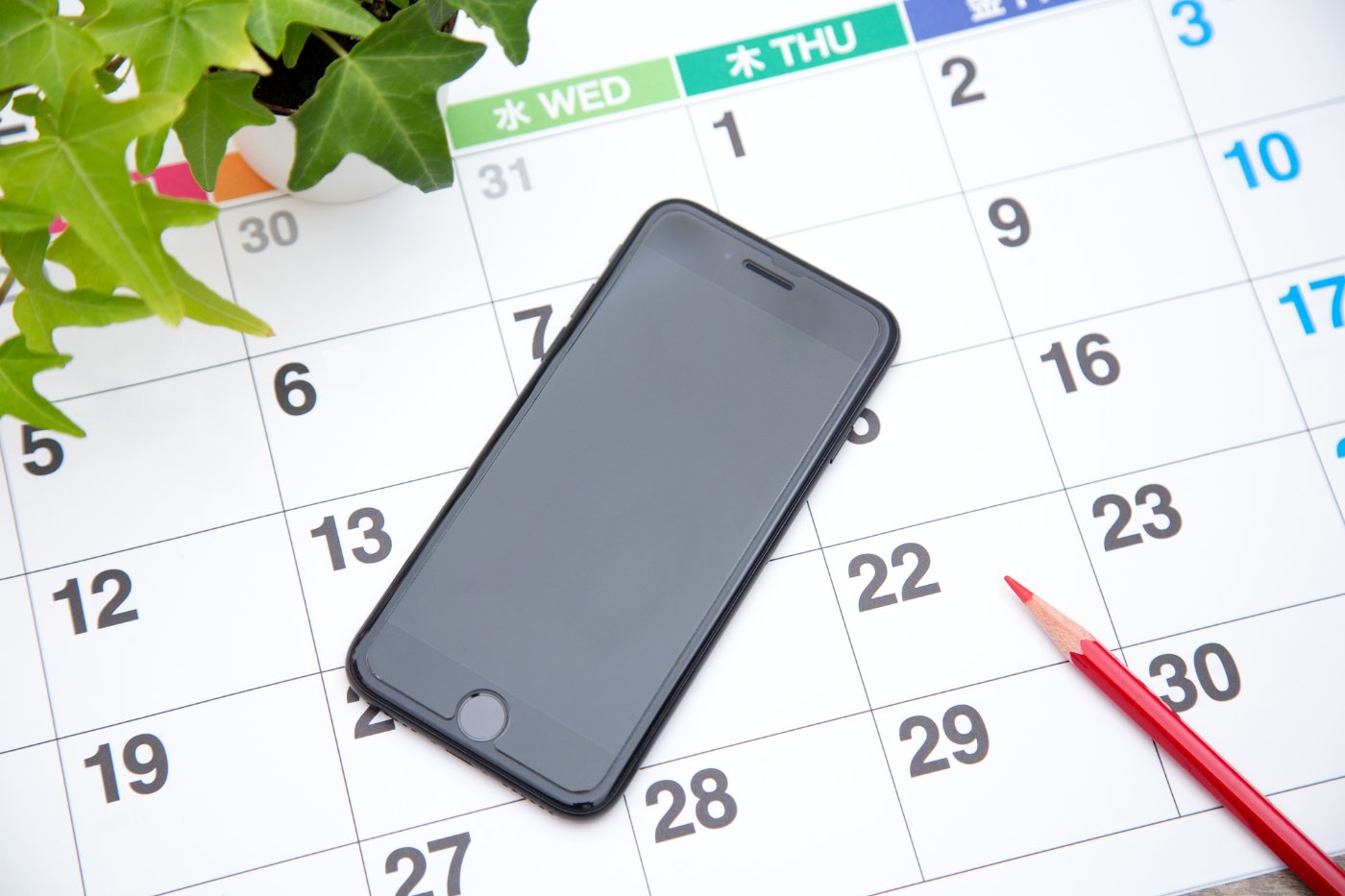 カレンダーとスマートフォンと赤鉛筆。制限が解ける日までの残り日数を数える