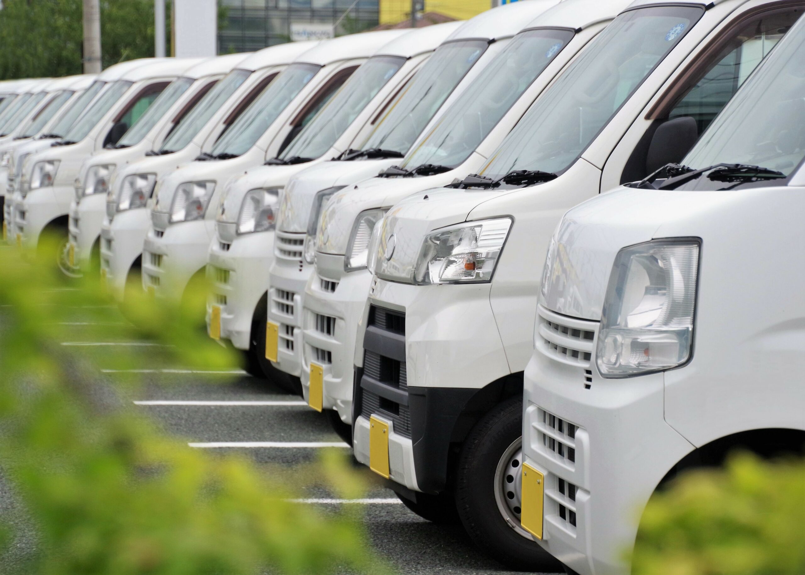 駐車場にずらりと並ぶ白い軽のビジネス車