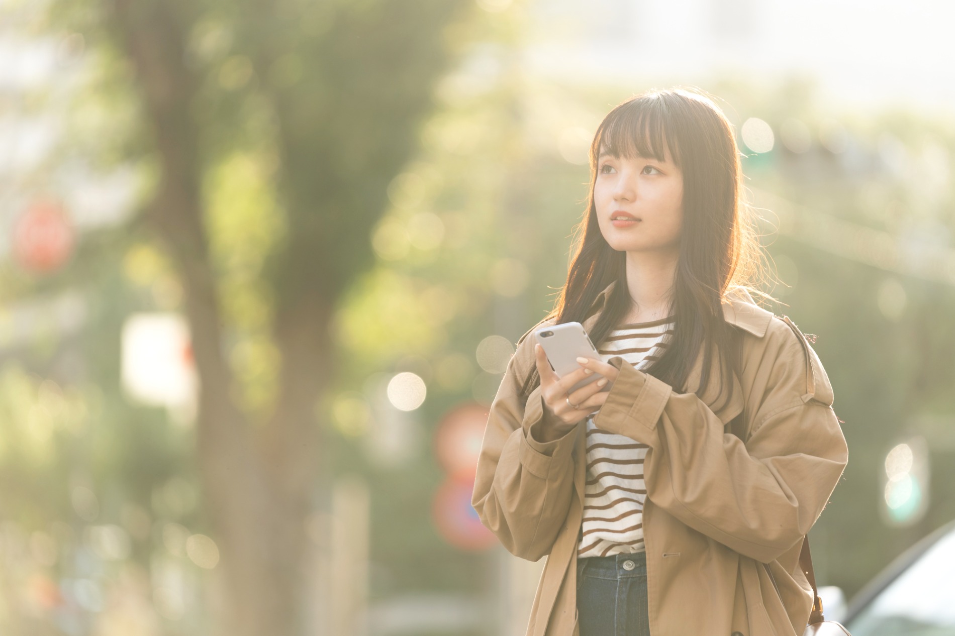 屋外でスマートフォンの画面を見ながら立ち止まっている人