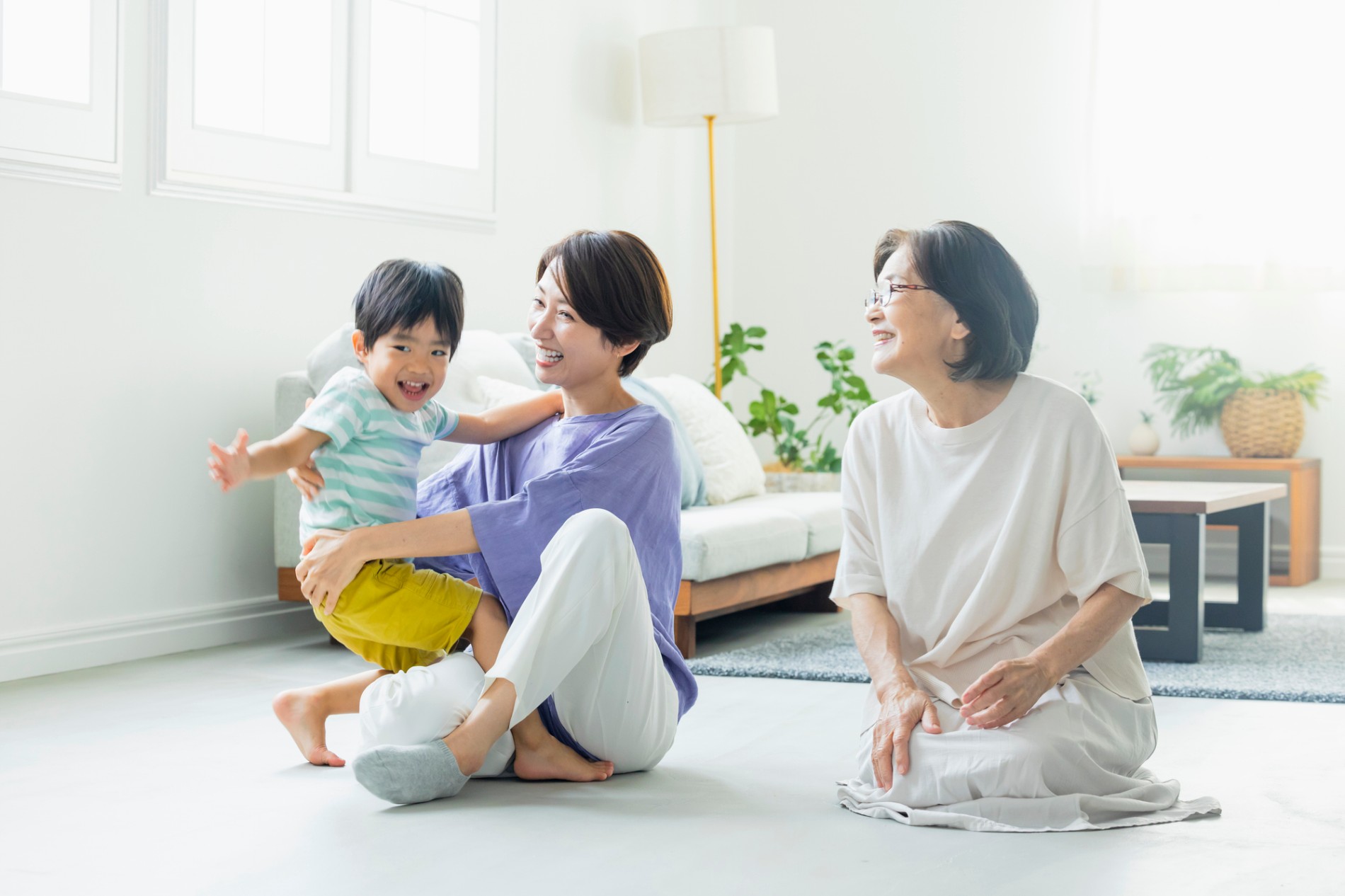 実家のリビングで三世代の家族が過ごしている様子