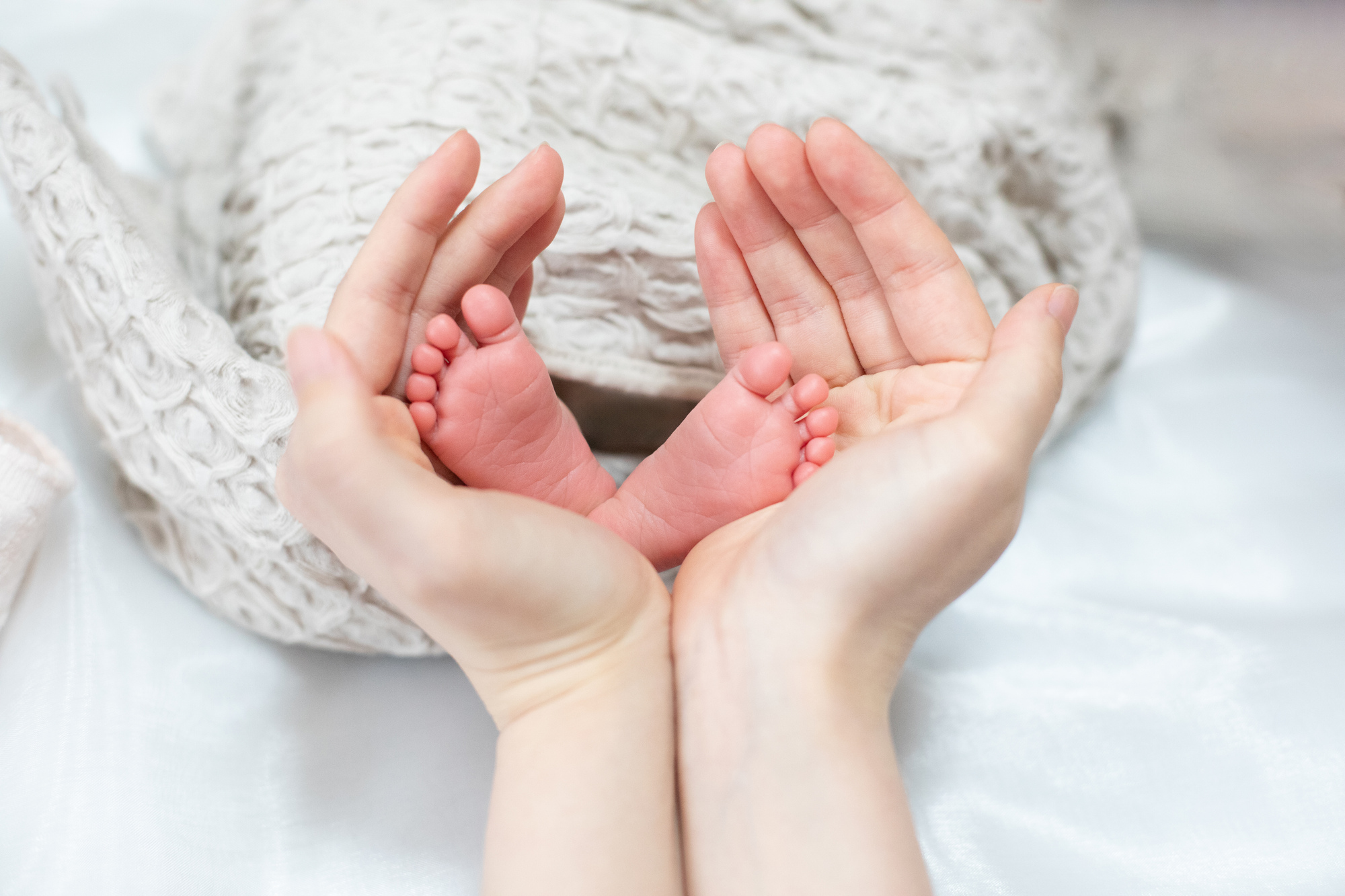 新生児の小さな足に母親の手が添えられている様子