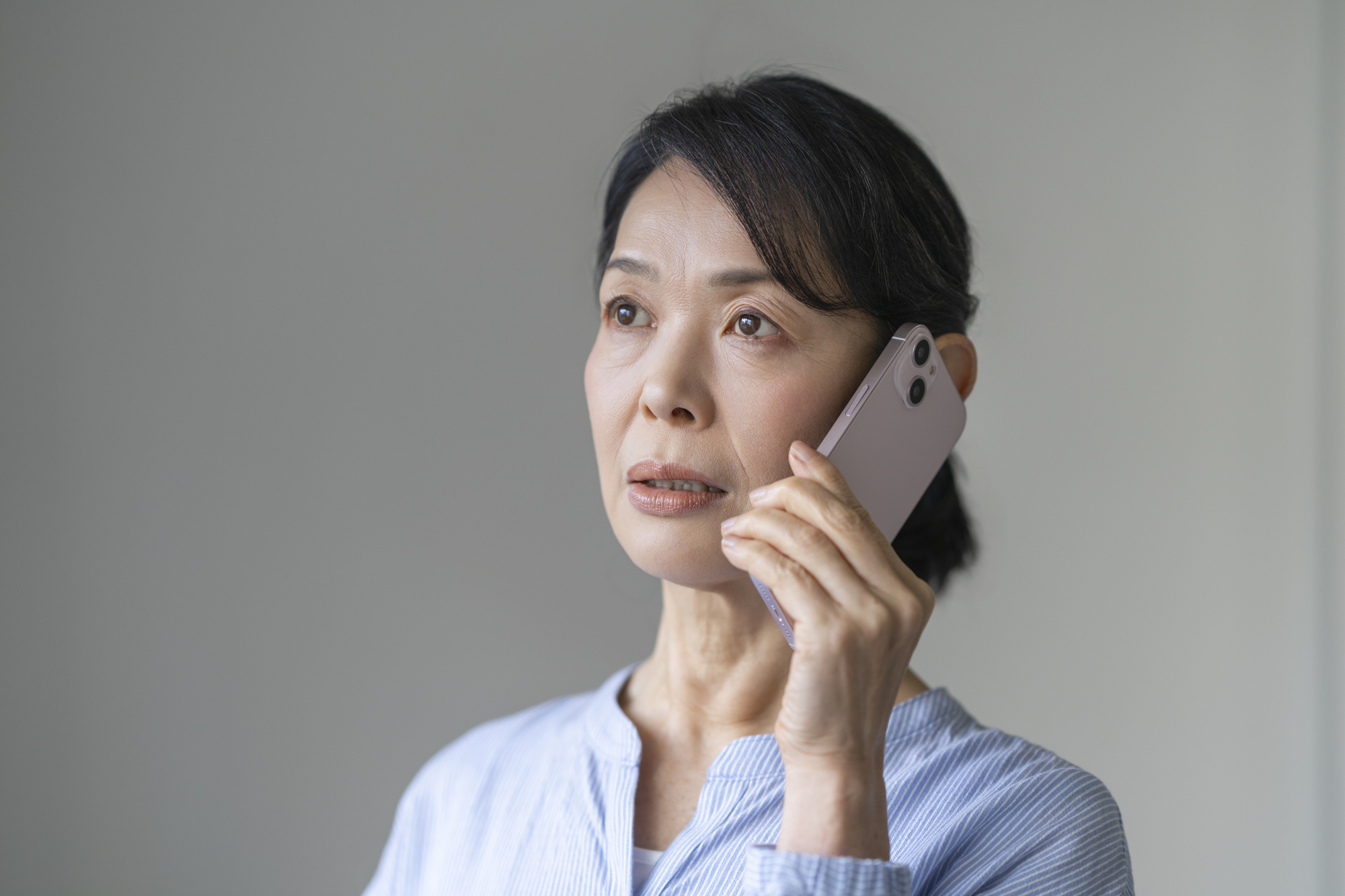 外出先でスマートフォンを耳に当てて通話している女性