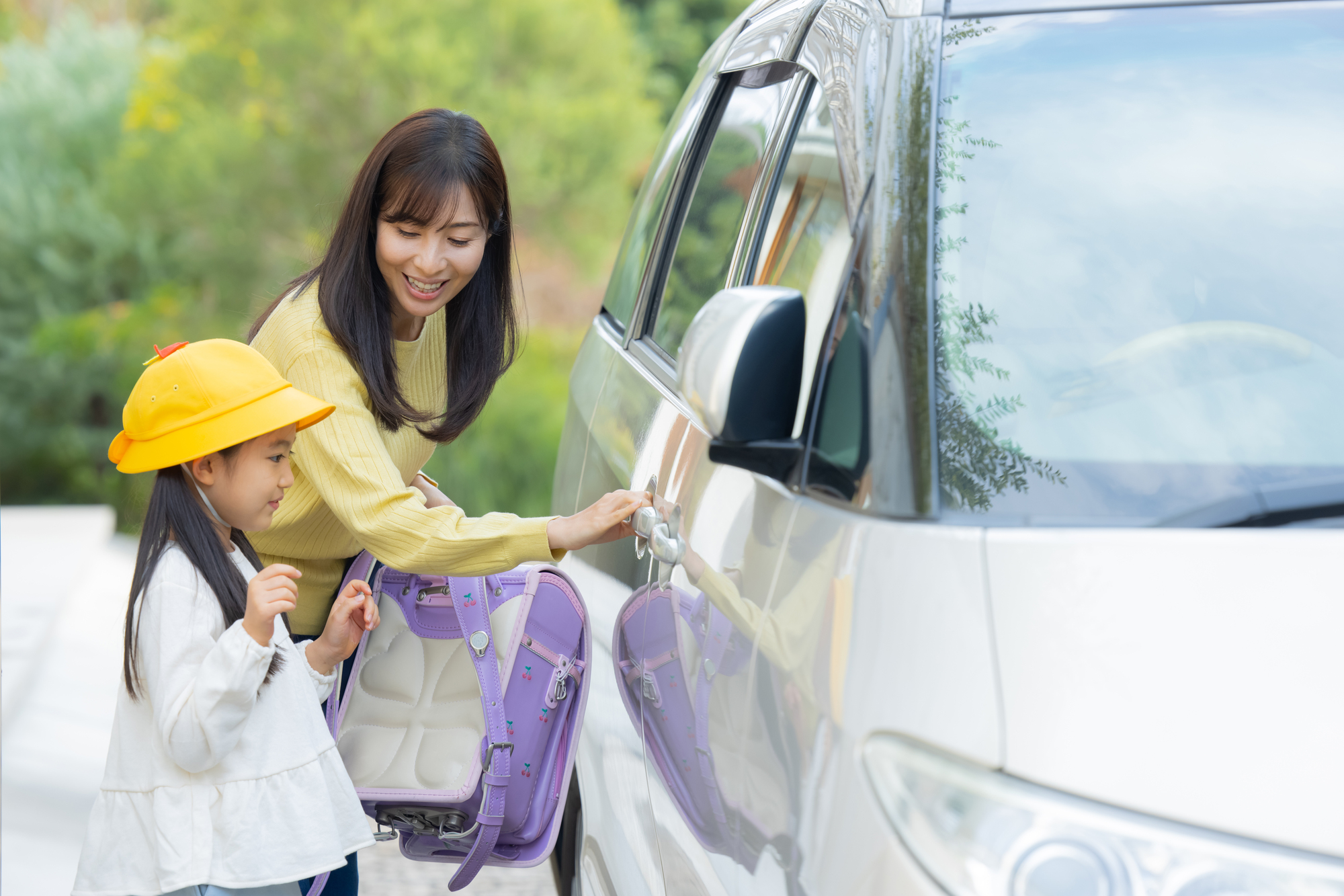 ランドセルを背負った小学生を車で送り出す朝の場面