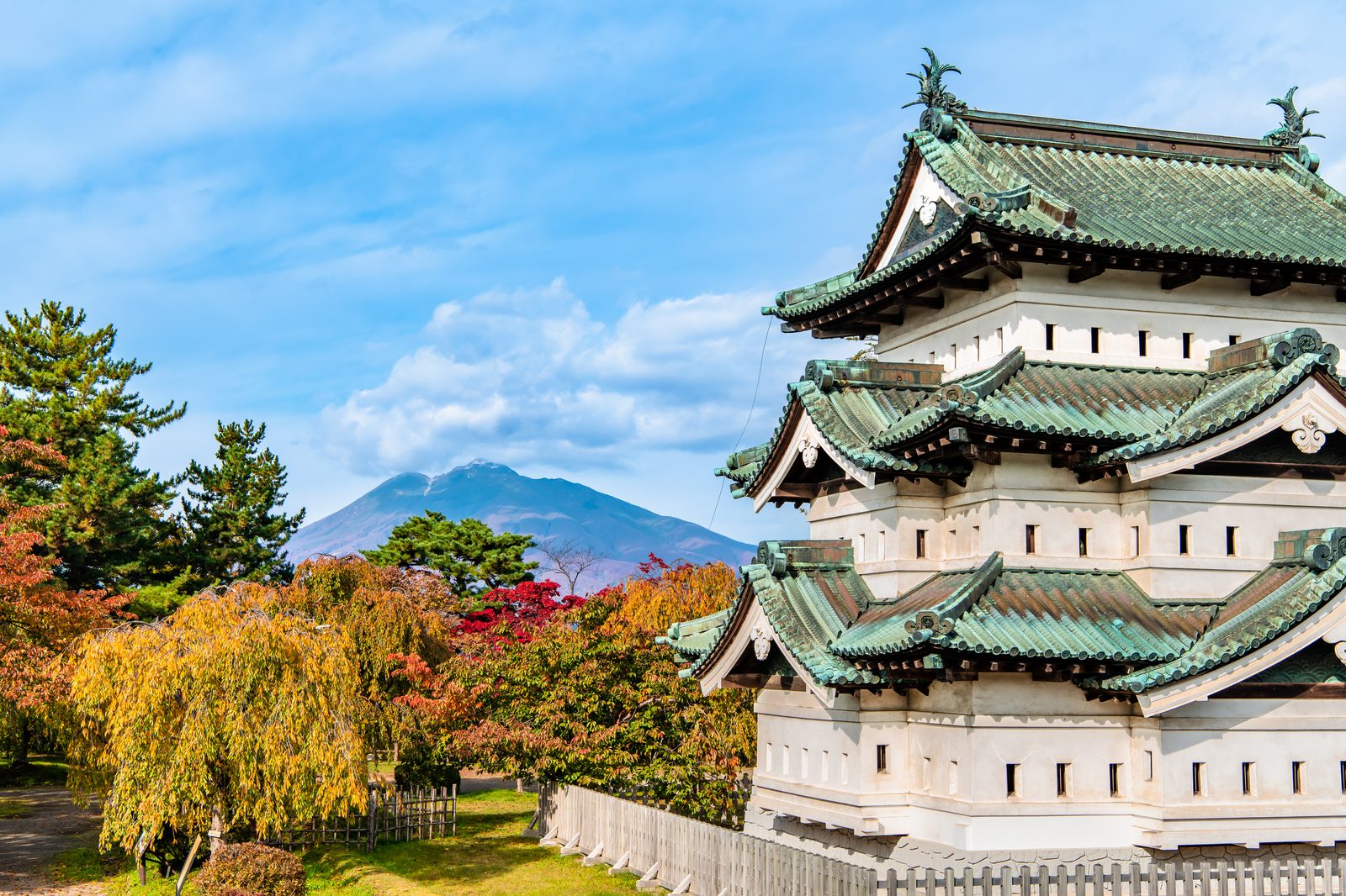 紅葉に染まる弘前城の天守と、背後にそびえる岩木山