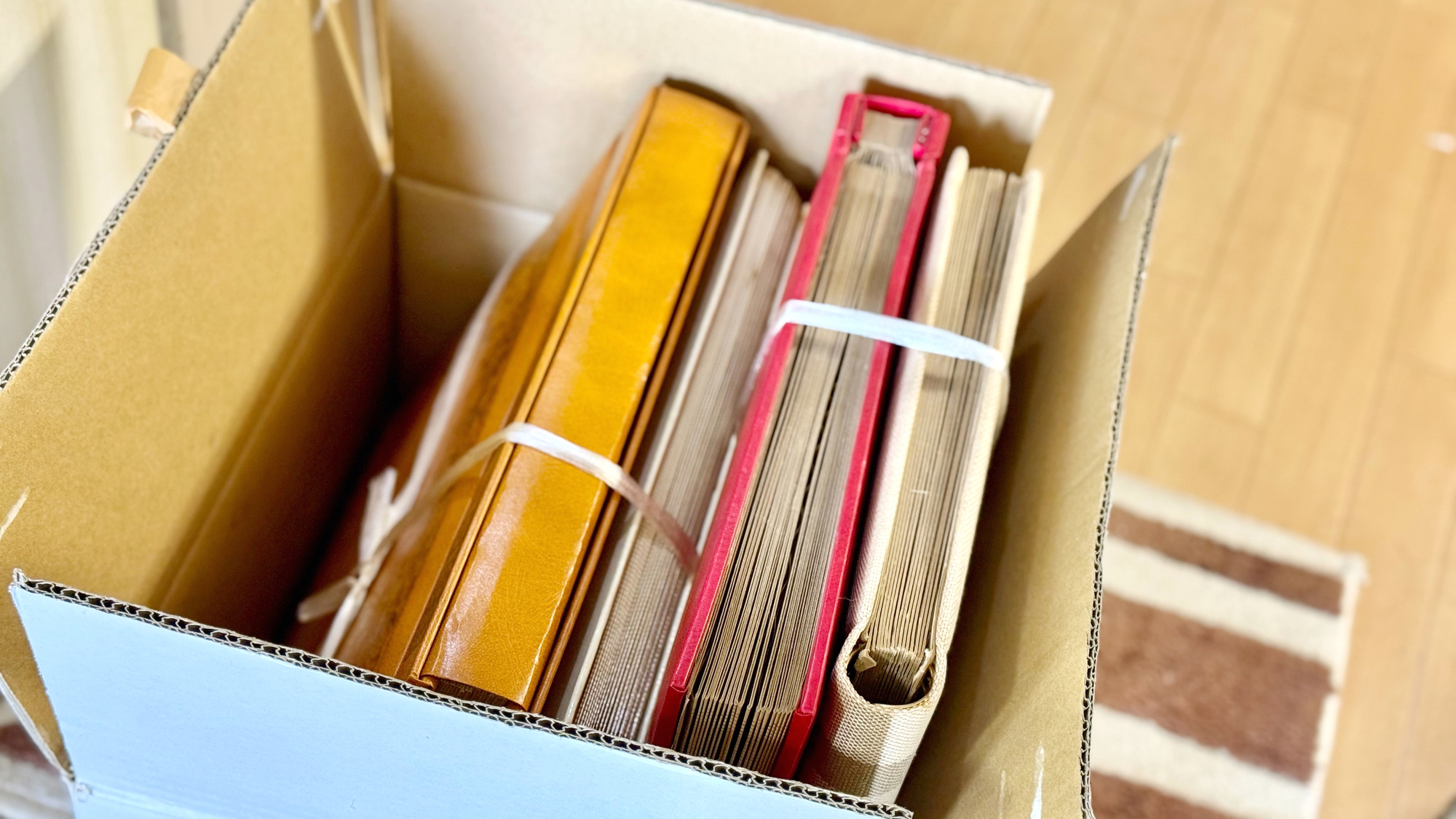 段ボール箱の中に、ひもでまとめた古いアルバムが何冊も入っている