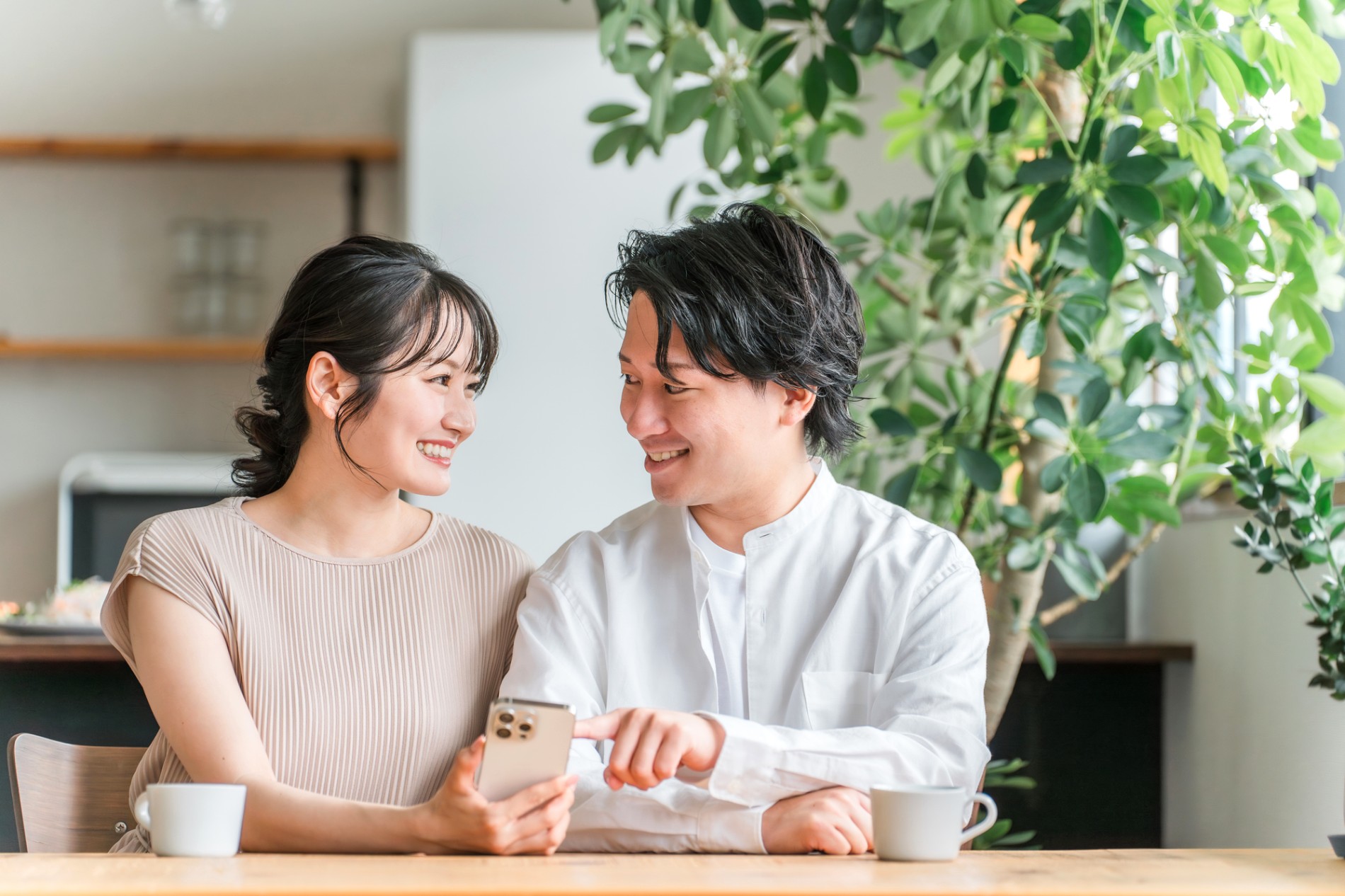 家でスマートフォンの画面を一緒に見る夫婦