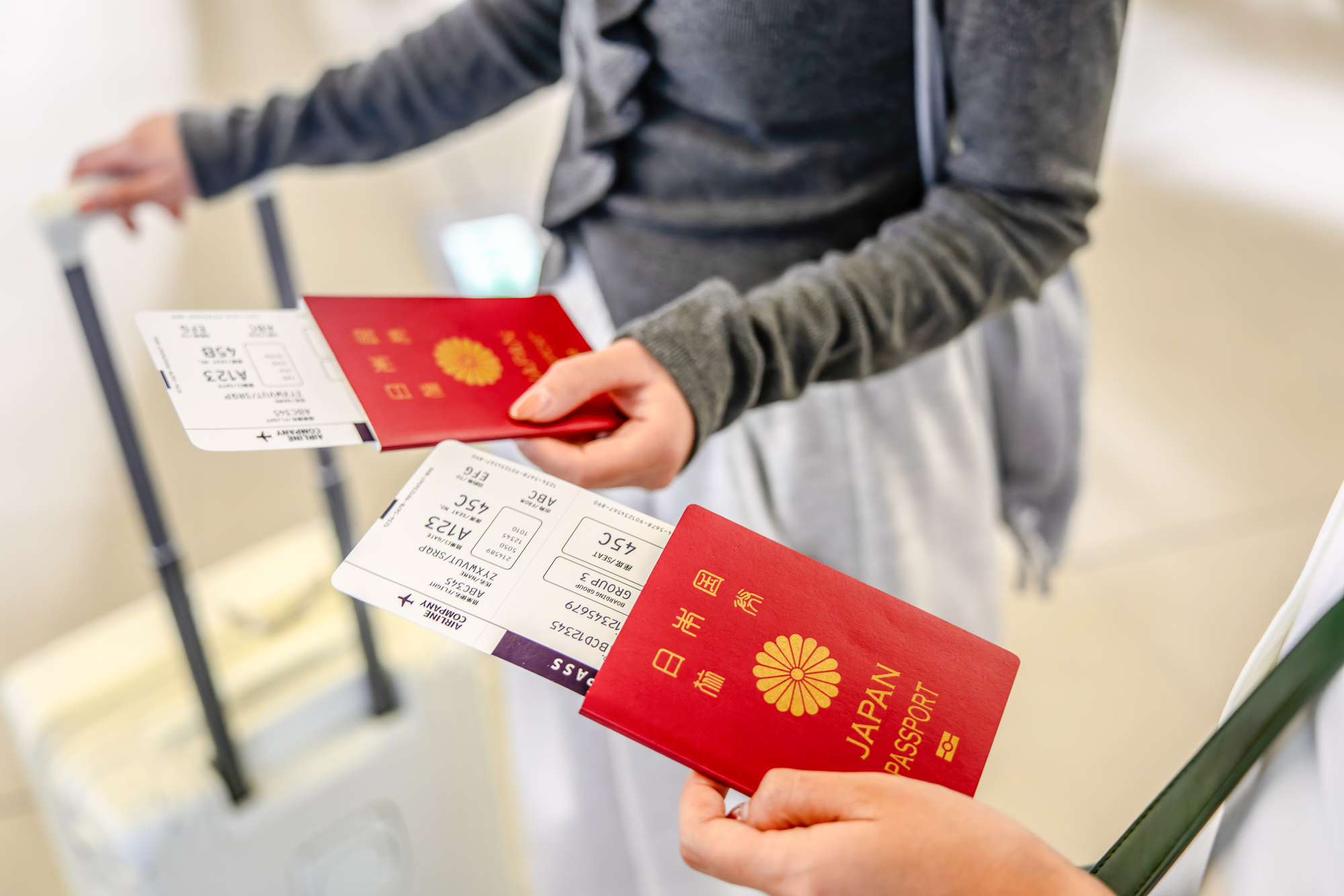 帰国便の搭乗券と日本のパスポートを手にした旅行者とスーツケース