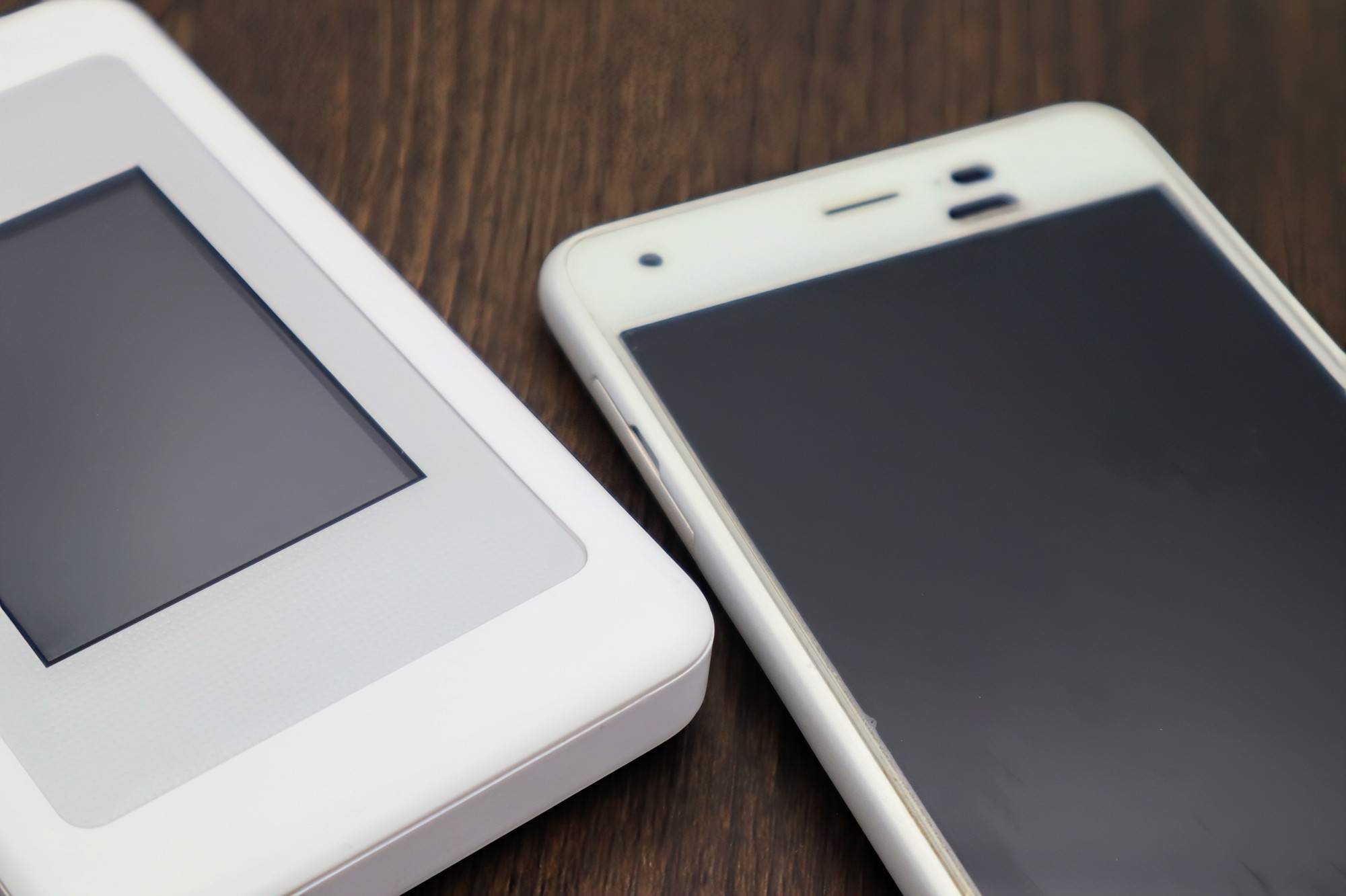 机に並べて置かれた小型の通信機器とスマートフォン