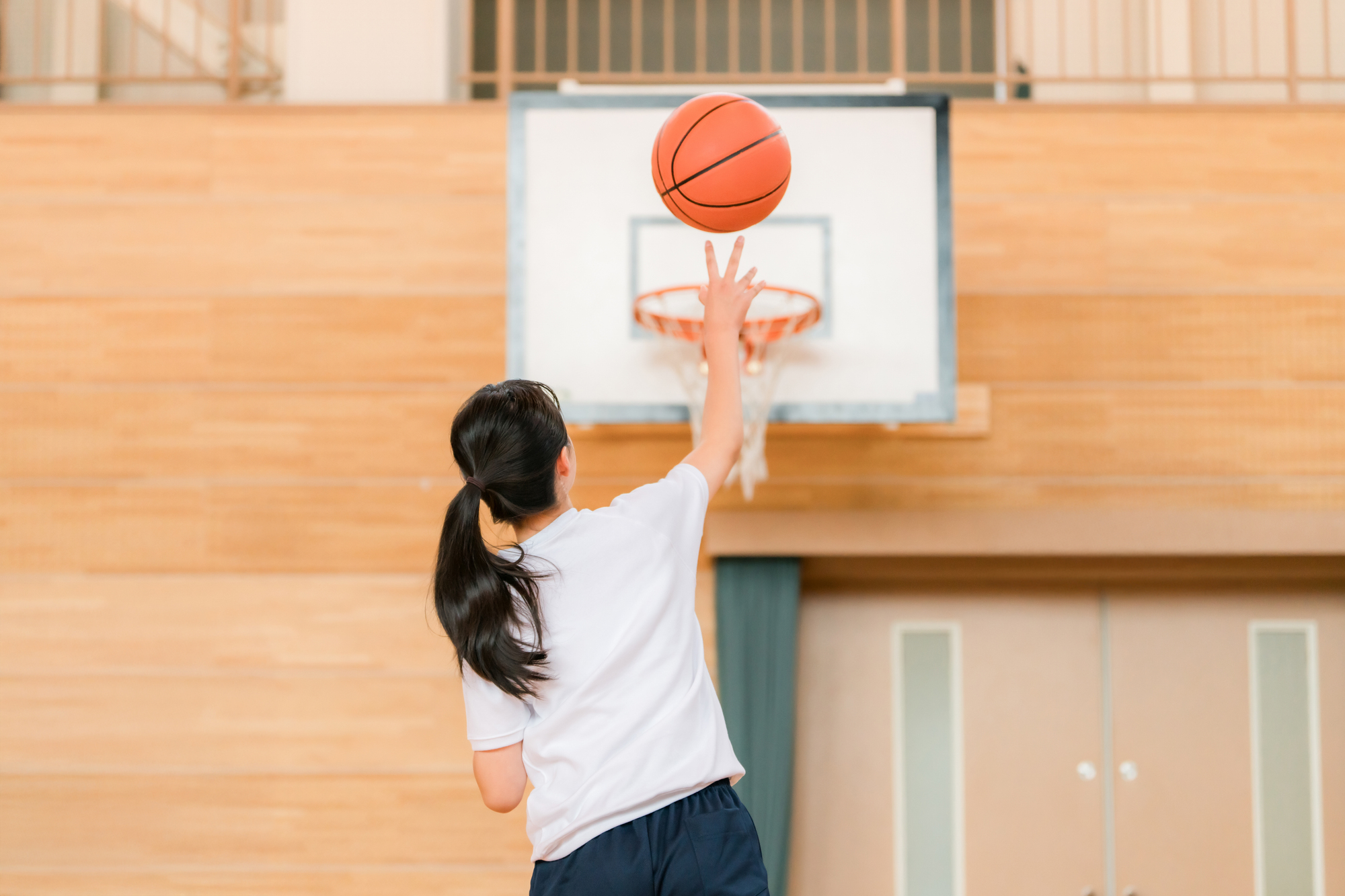 体育館でゴールに向かってシュートを放つ子ども