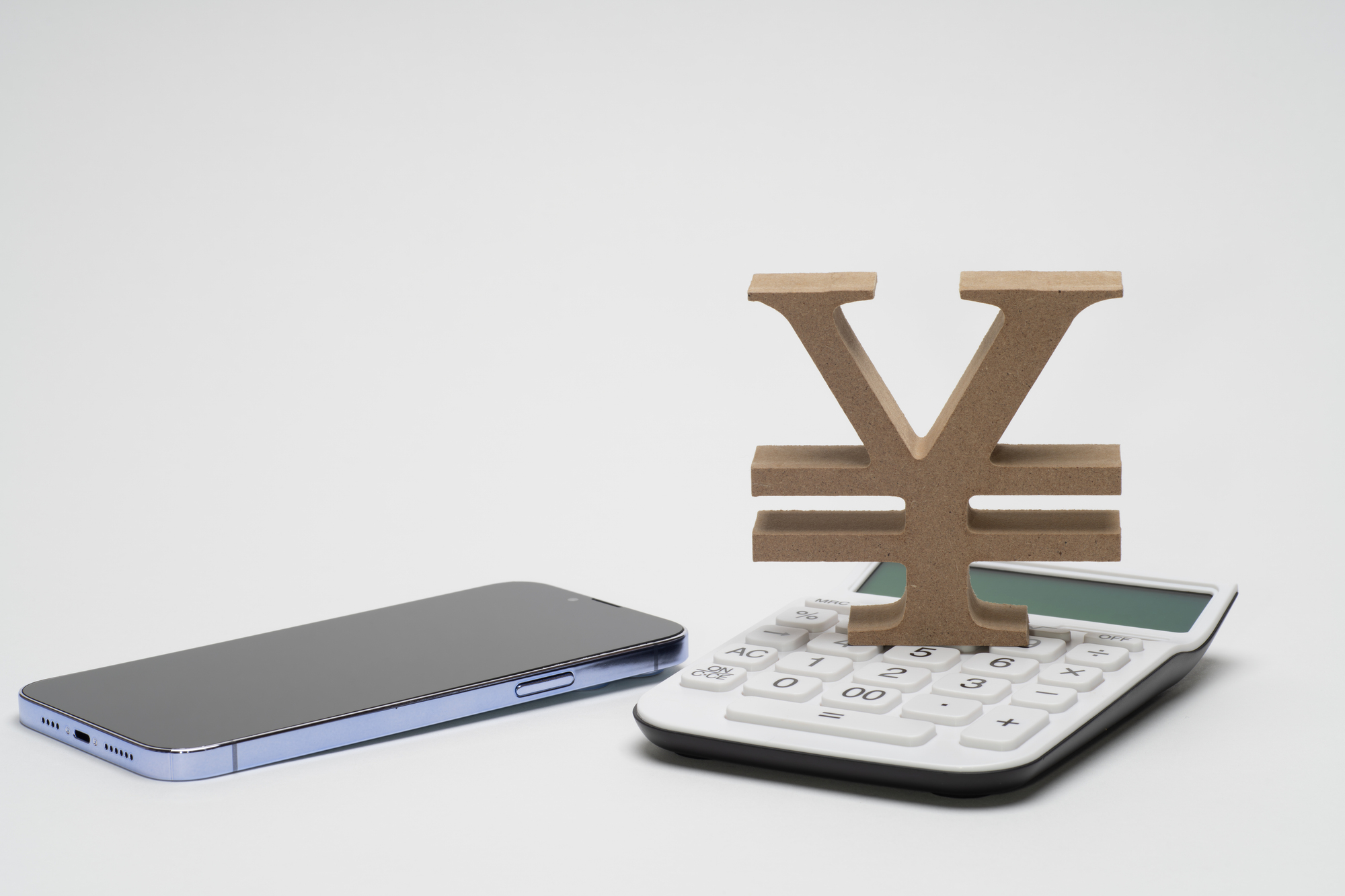 スマートフォンと電卓と円のマークを並べた通信費の見直しのイメージ