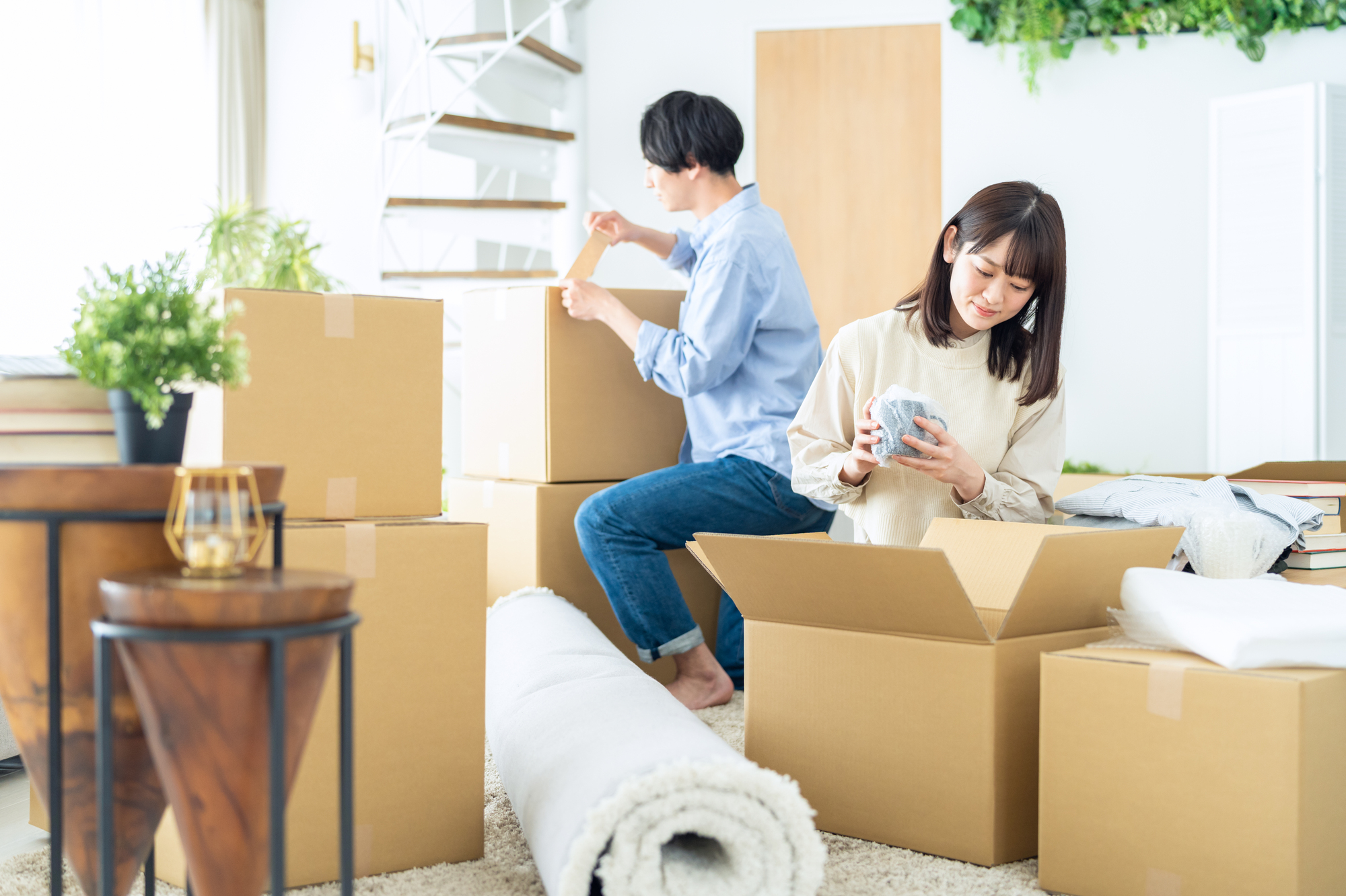 段ボールに囲まれてリビングで荷造りをする二人