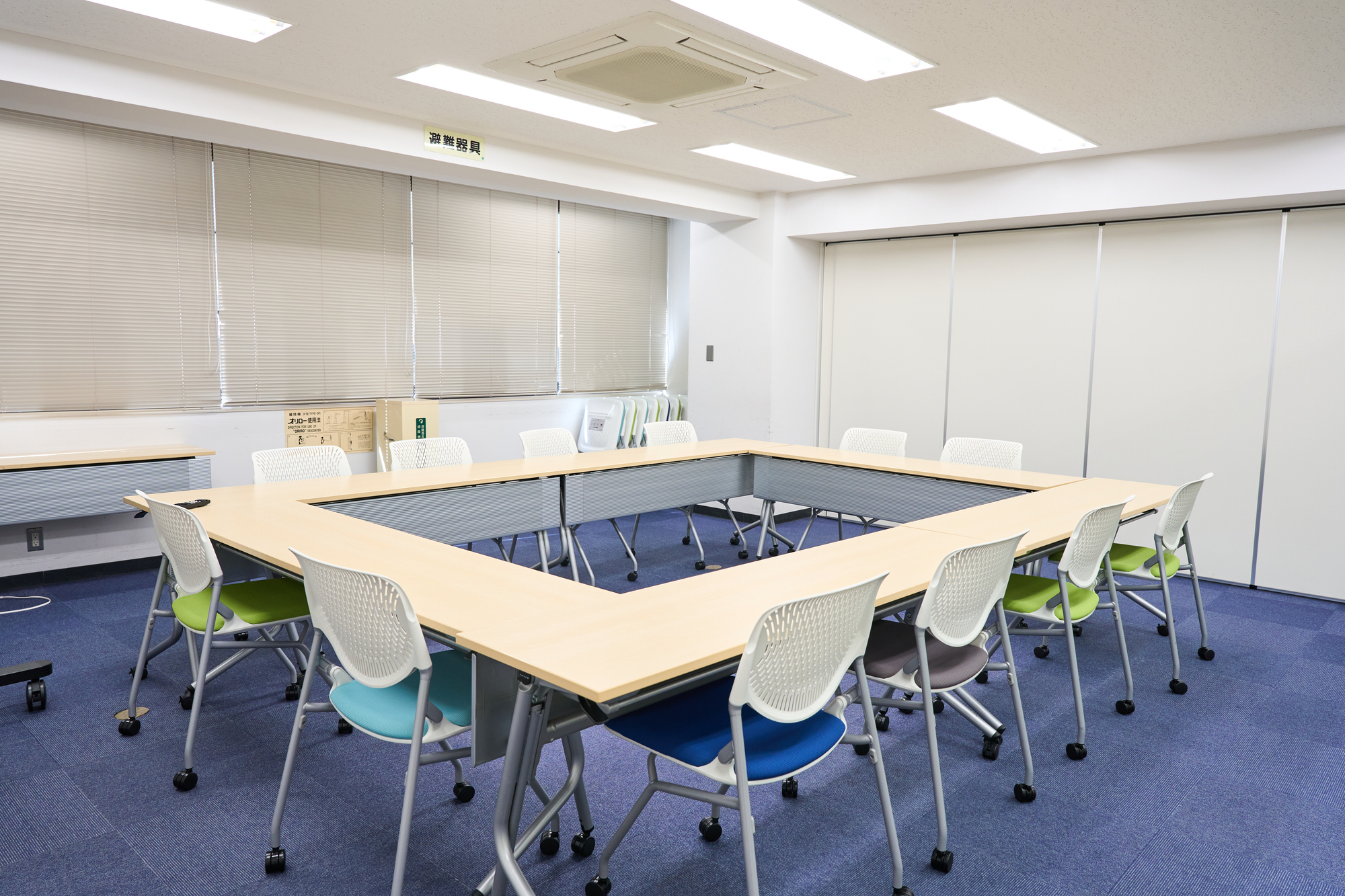 長机をロの字型に並べ、キャスター付きの椅子が置かれた誰もいない会議室