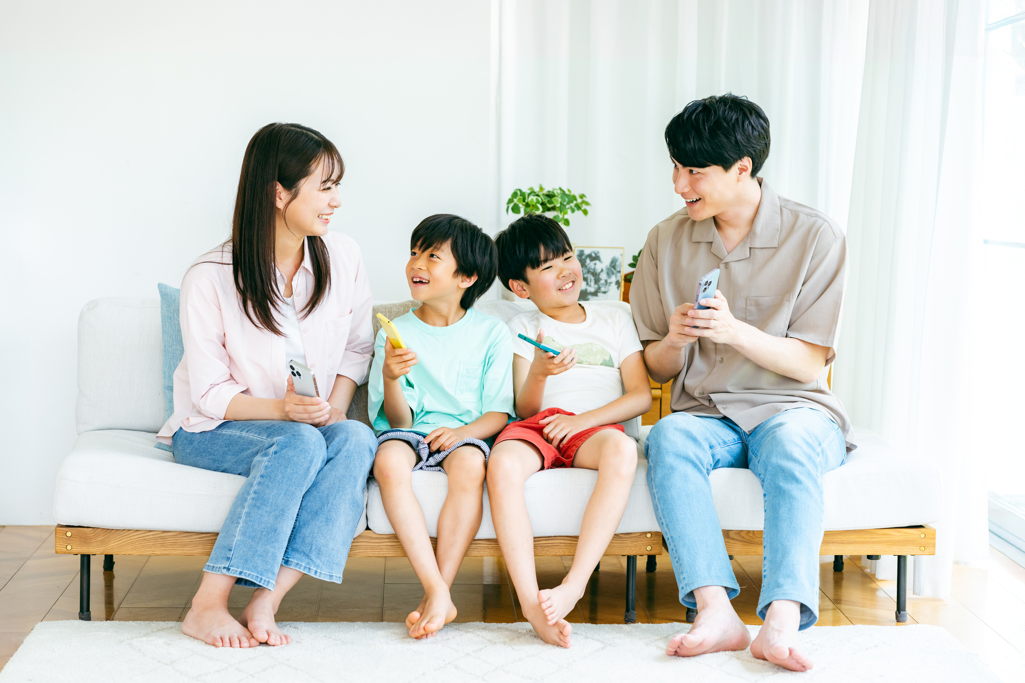 ソファに並んで座り、それぞれの端末を見ている家族