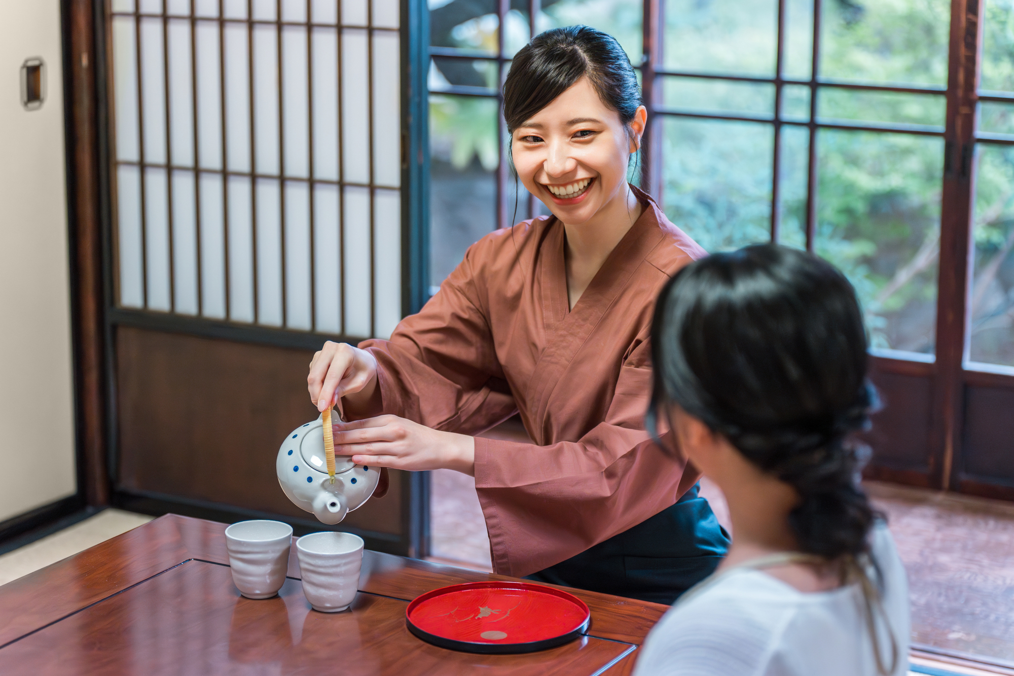 温泉旅館の客室でお茶を淹れる旅館スタッフの女性
